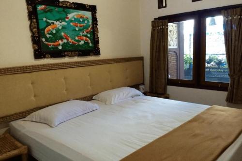 ein Bett mit zwei Kissen in einem Schlafzimmer mit einem Fenster in der Unterkunft Rapatmaja Mataram Homestay in Tjakranegara