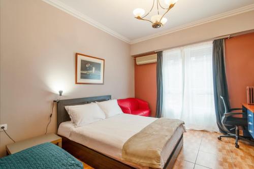 a small bedroom with a bed and a red chair at Charlie city center room in Athens