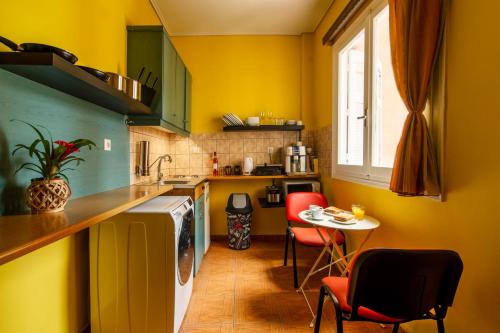 uma cozinha com paredes amarelas e uma mesa e cadeiras em Charlie city center room em Atenas