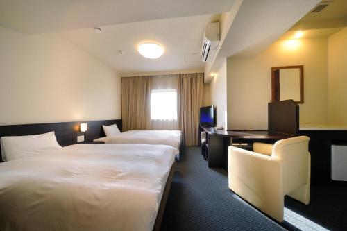 a hotel room with two beds and a desk at Dormy Inn Sendai Annex in Sendai