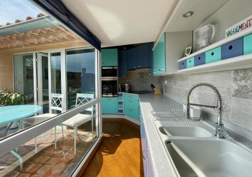 une cuisine avec des armoires bleues et un évier dans l'établissement L'Atypique - T3 grande terrasse, BBQ vue et cheminée, à Avignon