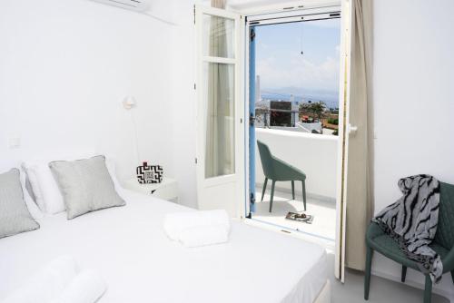 a bedroom with a bed and a chair and a window at Seaside Paros Ampelas in Ambelas