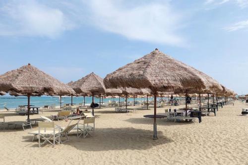 een strand met veel rieten parasols en stoelen bij Casa vacanze “Villa Paola” in Pescara