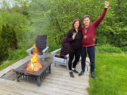 a man and a woman standing next to a fire at Sauerlandholiday in Diemelsee