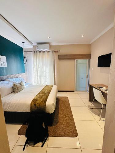 um quarto com uma cama, uma secretária e uma televisão em LIVE-INN LUXURY SUITES em Mahalapye