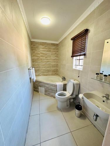 een badkamer met een toilet, een bad en een wastafel bij LIVE-INN LUXURY SUITES in Mahalapye