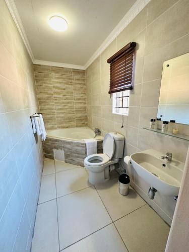 a bathroom with a toilet and a tub and a sink at LIVE-INN LUXURY SUITES in Mahalapye
