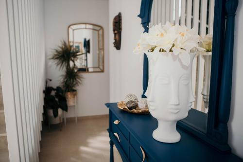 a blue dresser with a white vase with flowers in it at Flowers & Faces Guesthouse in Ponte de Lima