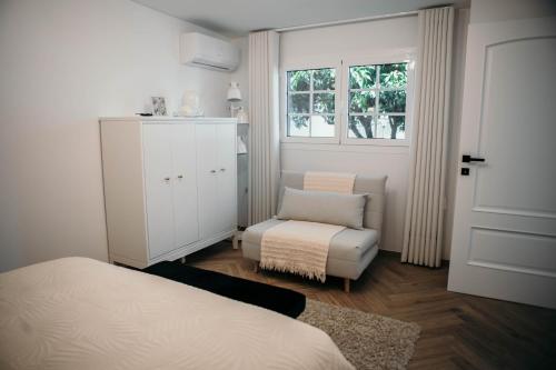 a bedroom with a bed and a chair and a window at Flowers & Faces Guesthouse in Ponte de Lima
