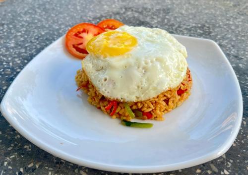 a white plate with an egg on top of rice at The Layar Homestay in Nusa Penida