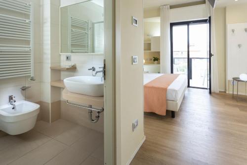 un bagno con lavandino, servizi igienici e un letto di Hotel 2000 con Piscina e Giardino a Riccione
