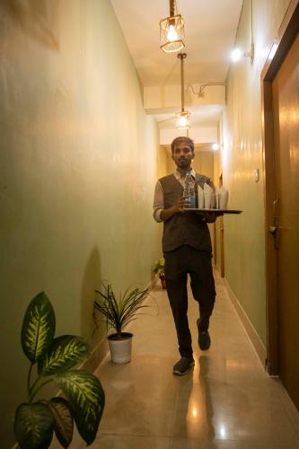 a man is holding a tray in a hallway at GS RESIDENCY in Guwahati