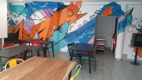 une chambre avec des tables et des chaises et une fresque murale. dans l'établissement HI Guarda - Pousada de Juventude, à Guarda