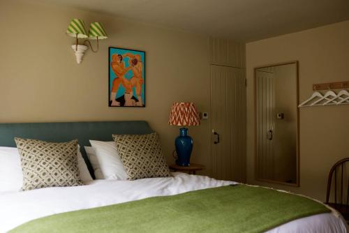 a bedroom with a bed with a green headboard at The Queen's Head in Broad Chalke