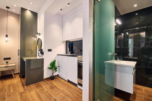 a kitchen with white cabinets and a green wall at Amuse Luxury Apartments in Zakynthos