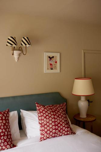 a bedroom with a bed with red pillows and a lamp at The Queen's Head in Broad Chalke