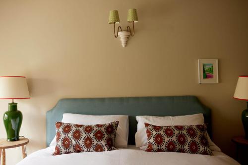 a bedroom with a bed with a green headboard and two lamps at The Queen's Head in Broad Chalke