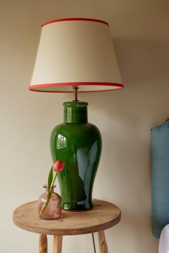 a green vase sitting on a table with a lamp at The Queen's Head in Broad Chalke