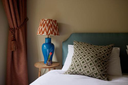 a bed with a blue lamp on a table with a pillow at The Queen's Head in Broad Chalke