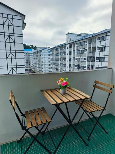 una mesa de madera y sillas en un balcón con edificios en Ayu Homestay en Tanah Rata