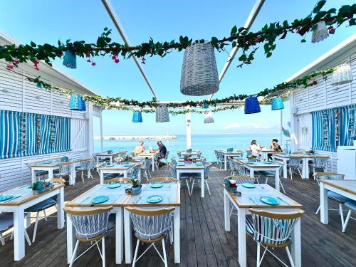 a restaurant with tables and chairs with the ocean in the background at Skipper Beachfront Suites in Hersonissos