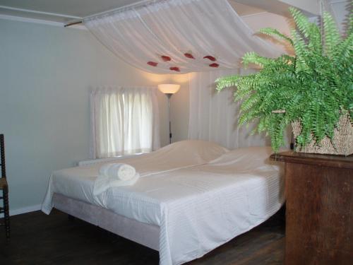 ein Schlafzimmer mit einem weißen Bett und einer Pflanze in der Unterkunft De Erfdijk in Herpen
