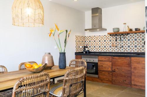 a kitchen with a wooden table with a bowl of fruit at Viladraga - Casa da Aguda in Colares