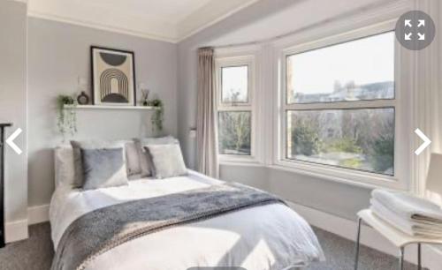 a white bedroom with a bed and two windows at Debenham Lodge Margate in Kent