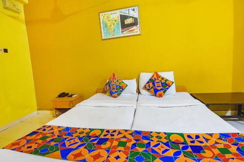 two beds in a room with a yellow wall at FabExpress Casa Paradiso, Panaji in Goa