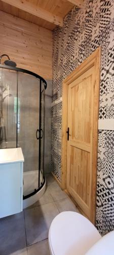 a bathroom with a shower and a wooden door at Letnisko BAJKA in Iława