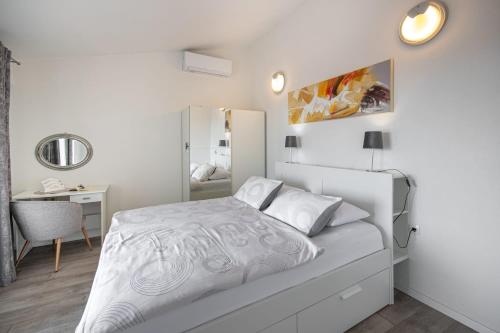 a white bedroom with a bed and a mirror at Apartments Villa Luce in Makarska