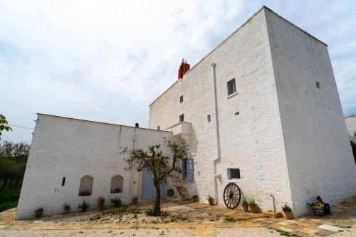 a large white building with a tree in front at Masseria Soluco in Monopoli