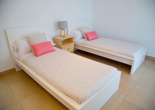 2 camas en una habitación con 2 almohadas rosas en Modern Villa in Cala Jondal Porroig, en Sant Josep de sa Talaia