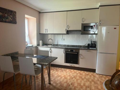 Apartamento Toki Berriya في إليزوندو: مطبخ به أجهزة بيضاء وطاولة وكراسي