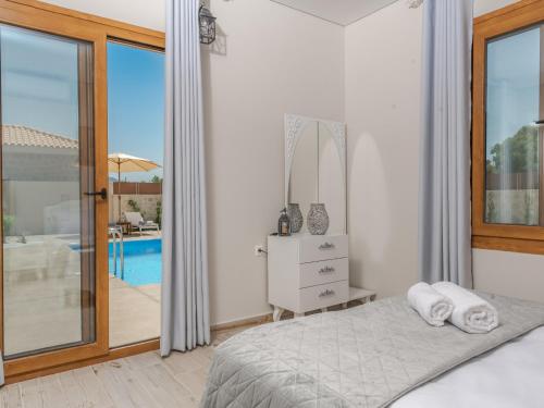 een slaapkamer met een bed en uitzicht op een zwembad bij Villa Aqua - Laganas Stone Villas in Laganas