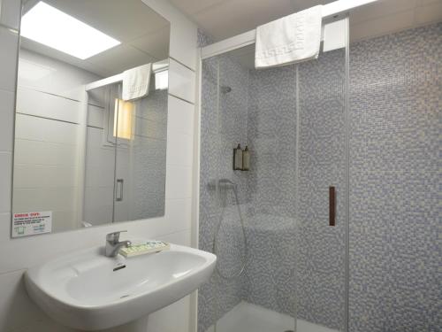 baño con lavabo y ducha con puerta de cristal en Apartamentos Arlanza - Only Adults, en Playa d'en Bossa