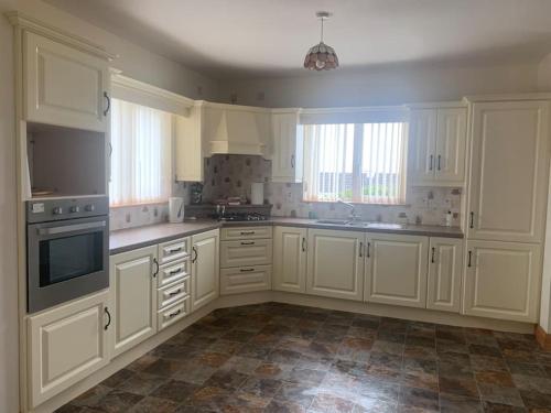 a large white kitchen with white cabinets and appliances at Mickey's House in Annagry