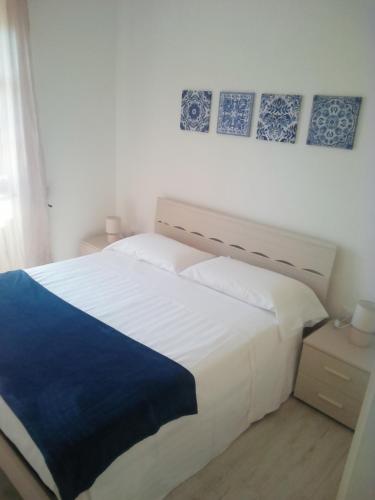 een slaapkamer met een groot wit bed met blauwe accenten bij CASA VACANZA YDROUS in Otranto
