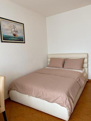 een bed in een slaapkamer met een foto aan de muur bij Apartmani Stanojevic in Kotor