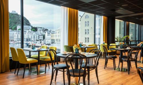 um restaurante com mesas e cadeiras e uma grande janela em Thon Hotel Ålesund em Ålesund