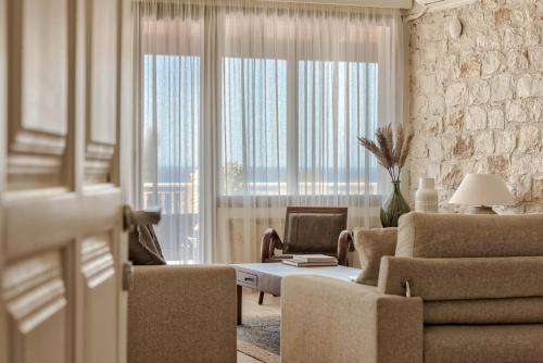 uma sala de estar com um sofá e cadeiras e uma grande janela em Ananta Blue Residence em Argasi