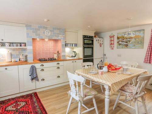 a kitchen with a table and chairs in a kitchen at Milton Cottage, Nr Thurlestone - a delightful thatched cottage close to the beach in Thurlestone