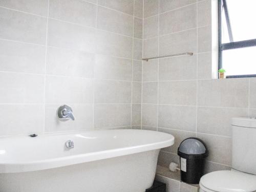 a bathroom with a white tub and a toilet at 1254 The Blyde Crystal Clear 3 Bedroom Garden Apartment in Pretoria