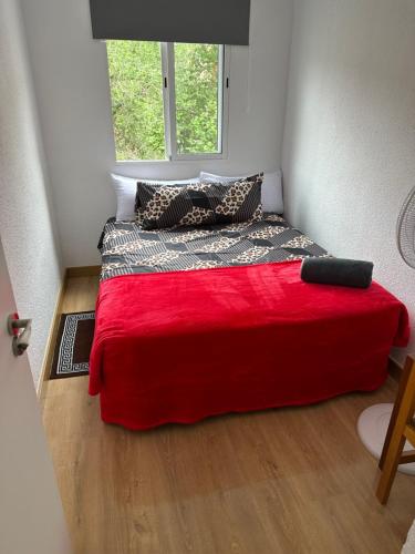 um quarto com uma cama com um cobertor vermelho e uma janela em El Gengo Hostel em Madri