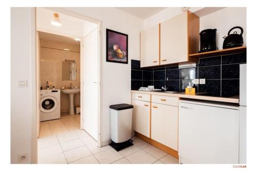 une cuisine avec des armoires blanches et une laveuse et une sécheuse dans l'établissement Appartement vue mer & port à La Turballe, à La Turballe