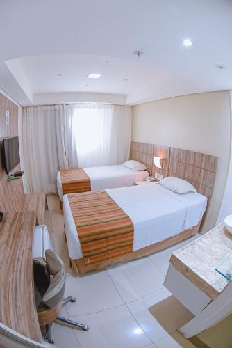 a hotel room with two beds and a desk at Profissionalle Hotel São Luís in São Luís