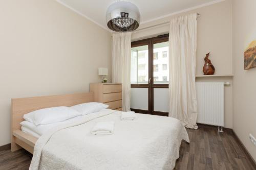 a white bedroom with a large bed and a window at Apartments Warsaw Giełdowa 4 by Renters in Warsaw