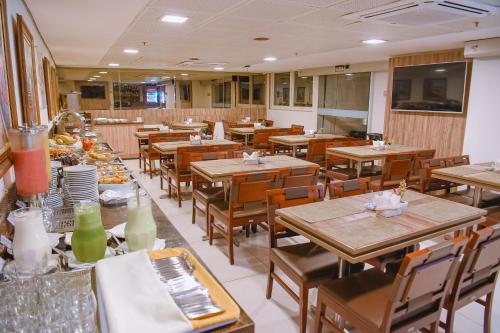 an empty restaurant with wooden tables and chairs at Profissionalle Hotel São Luís in São Luís
