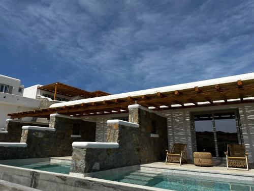 a patio with two chairs and a swimming pool at Abelos Mykonos in M&yacute;konos City