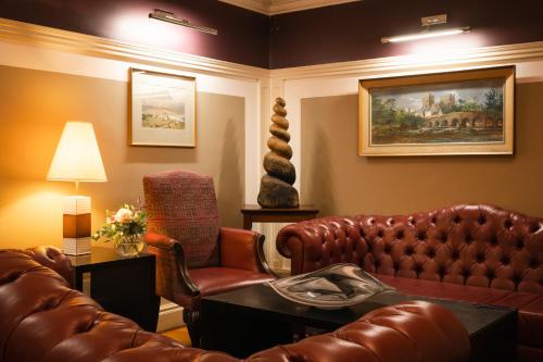 a living room with a leather couch and a chair at Castle Hotel Macroom in Macroom